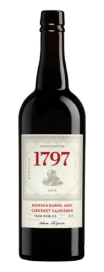 Port bottle labeled as 1797 with a cream label. The brand name 1797 is in red. There's a drawing of 3 barrels in the middle with western inspired decorative edging around it. The wine is labeled a Bourbon Barrel aged Cabernet Sauvignon 2019 from Paso Robles and signed by winemaker Adam LaZarre.
