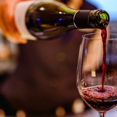 A server pours red wine into a wine glass.